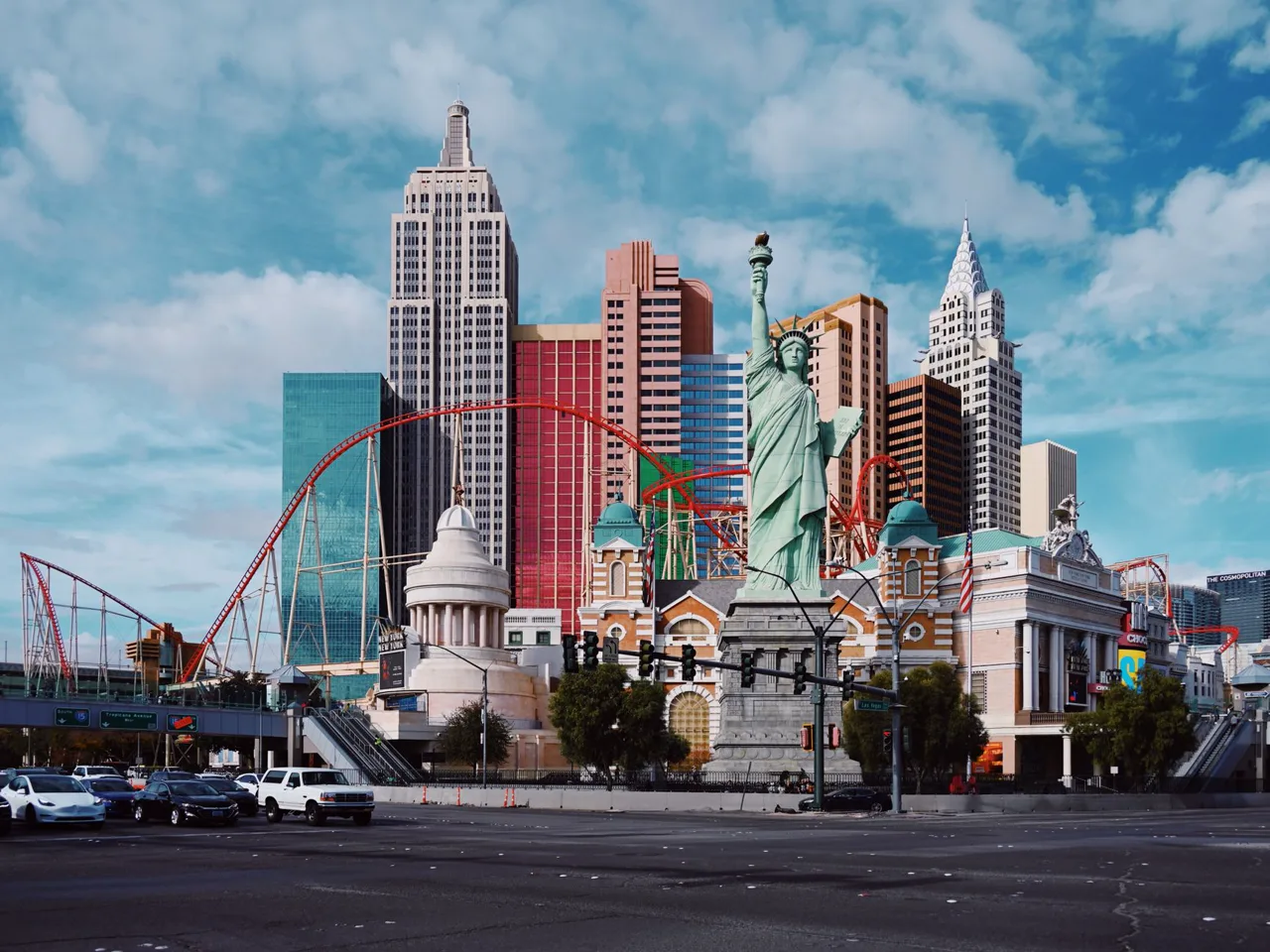 Daytime street-level view of a Las Vegas resort's mock Manhattan skyline with a green Statue of Liberty replica
